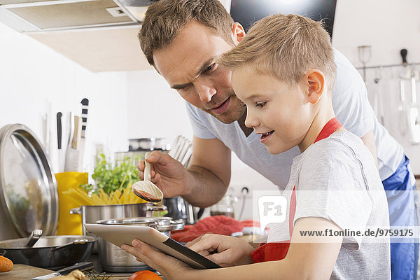 Father and son cooking together using digital tablet