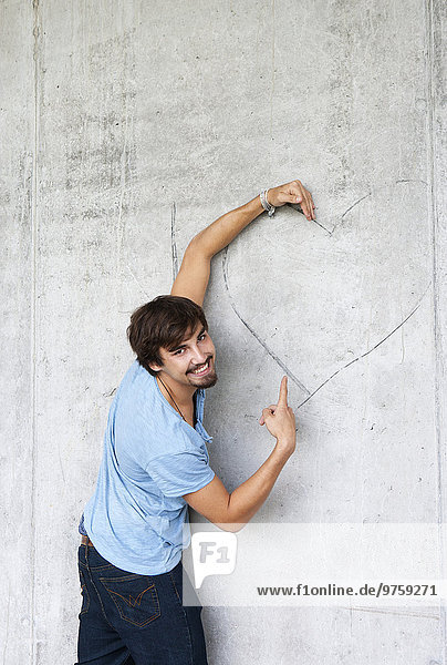 Mann umarmt Graffiti-Herz an der Betonwand