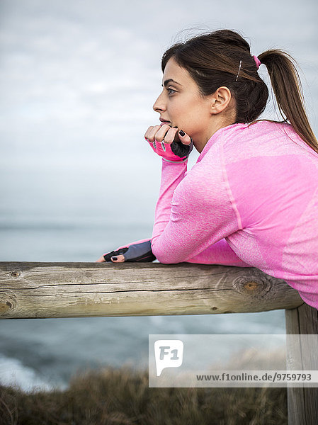 Spanien,  Gijon,  sportliche junge Frau an der Küste mit Blick auf die Küste