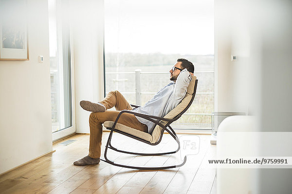 Young man sitting on rocking chair relaxing