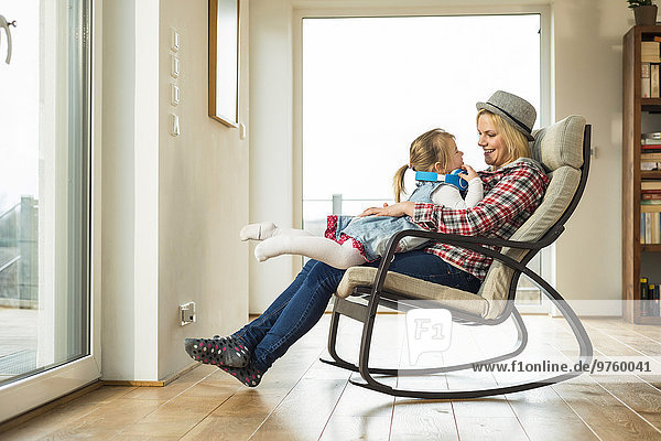 Mother and daughter on rocking chair with headphones
