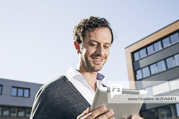Portrait of smiling businessman looking at digital tablet