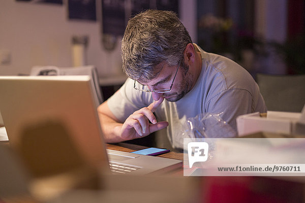 Mann mit Laptop und Smartphone am Schreibtisch