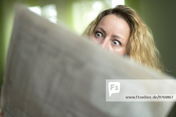 Horrified woman reading newspaper