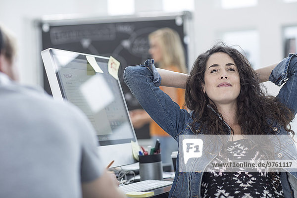 Kreative Bürofrau entspannt mit den Händen hinter dem Kopf