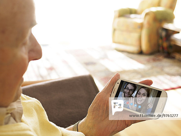 Grandfather videoconferencing with grandchildren via smartphone