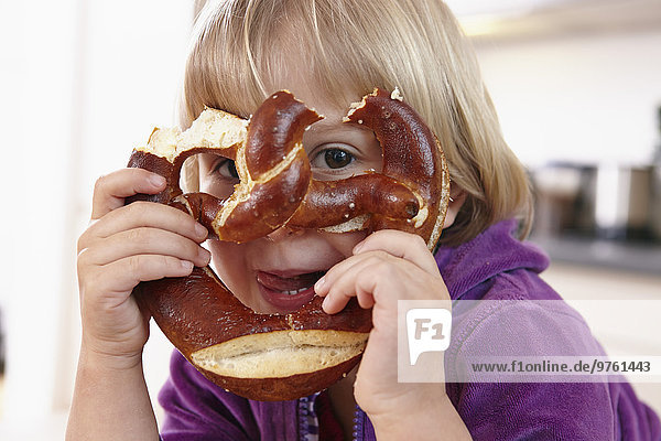 Little girl looking through pretzel