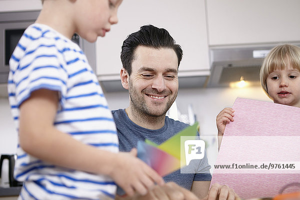 Father tinkering in kitchen with son and daughter