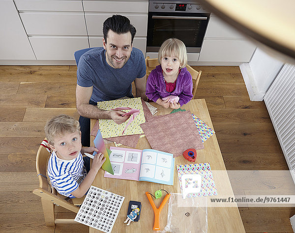 Vater bastelt in der Küche mit Sohn und Tochter