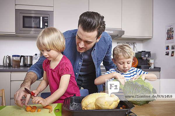 Father preparing food in kitchen with children