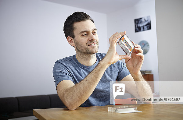 Man looking at old music cassette