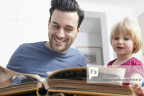 Father looking at photo album with kids
