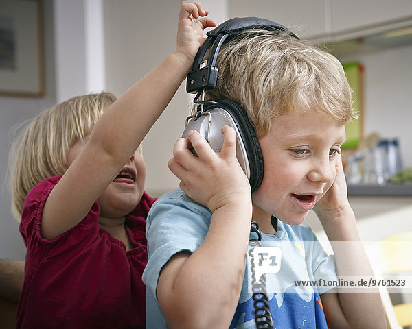 Brother and sister listening to music with headphones