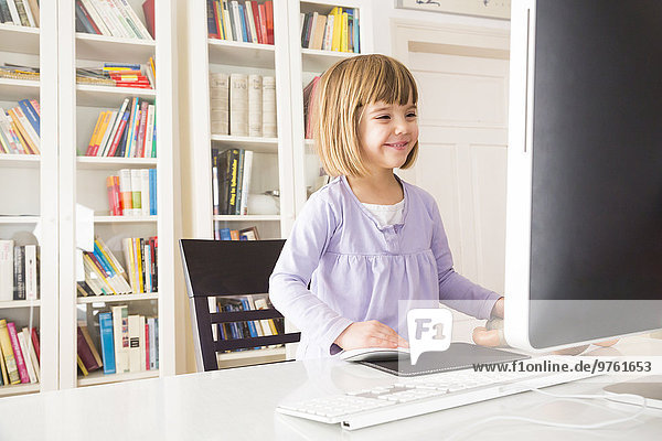 Smiling little girl spending time at computer