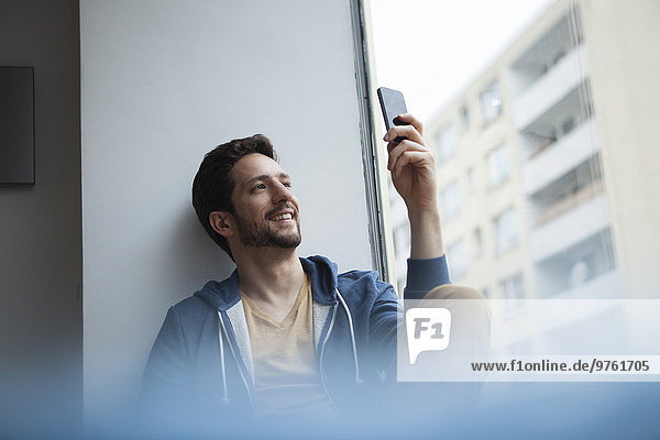 Smiling man taking a selfie with his smartphone