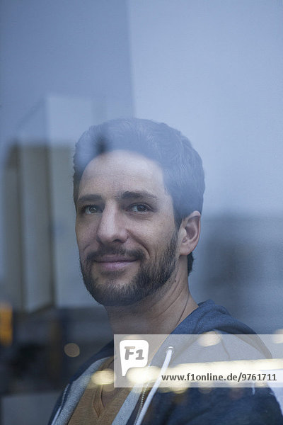 Portrait of smiling man with beard looking through window