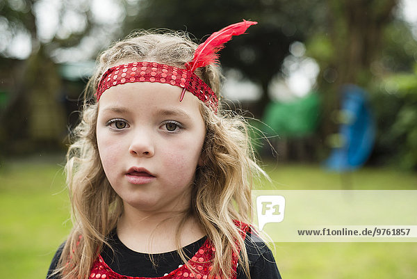 Porträt des kleinen Mädchens mit rotem Haarreif und Feder