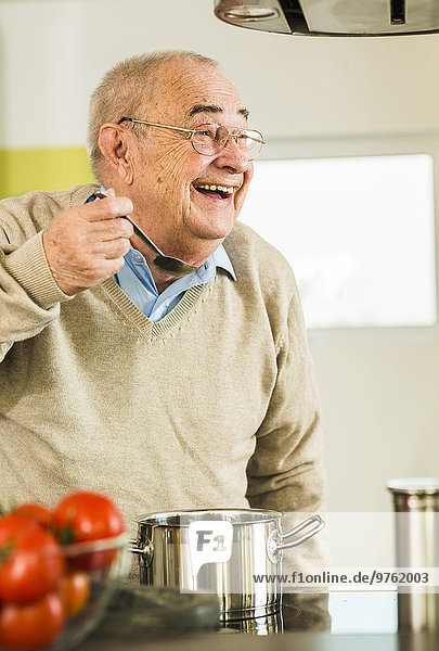 Glückliche Seniorenverkostung aus dem Kochtopf in der Küche