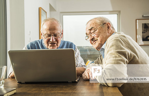 Two senior friends looking at laptop
