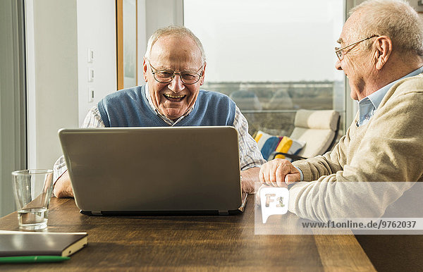 Zwei ältere Freunde beim Blick auf den Laptop