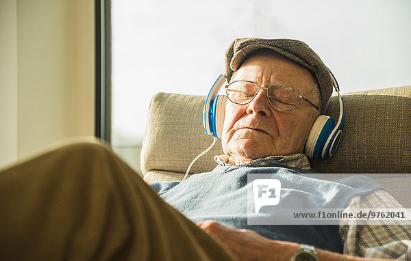 Senior Mann zu Hause entspannt mit Kopfhörer