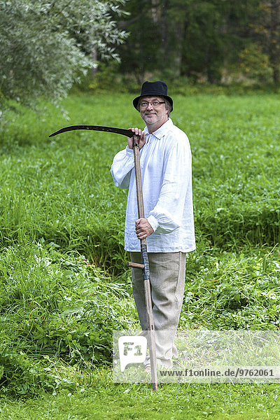 Estland  Porträt eines lächelnden Bauern mit Sense