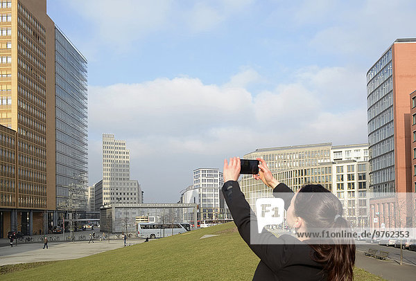 Deutschland  Berlin  Geschäftsfrau beim Fotografieren von Smartphones