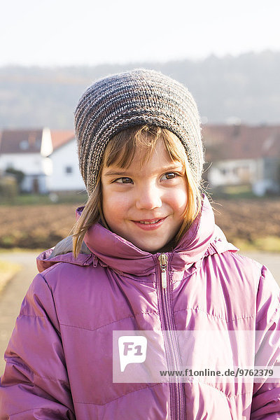 Portrait of little girl wearing woolly hat and pink winter jacket