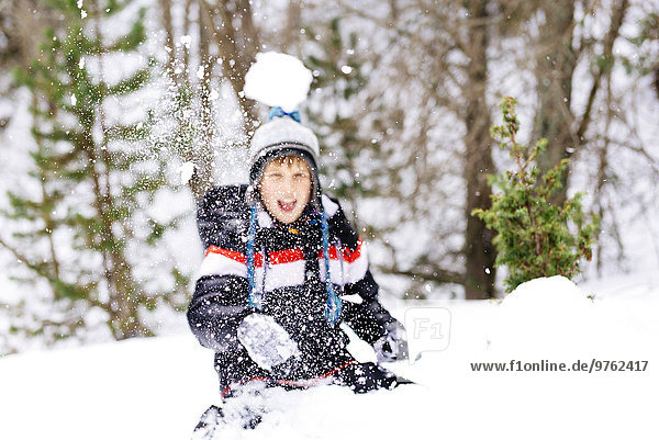 Happy boy throwing a snowball in the woods