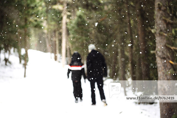 Man and child walking through the forest while snowing