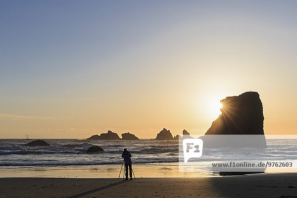 USA  Oregon  Bandon  Bandon Beach  Rocky needles at sunset  female fotographer at beach