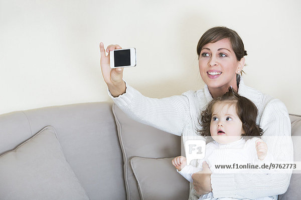 Frau nimmt Selfie mit ihrer Tochter auf die Couch