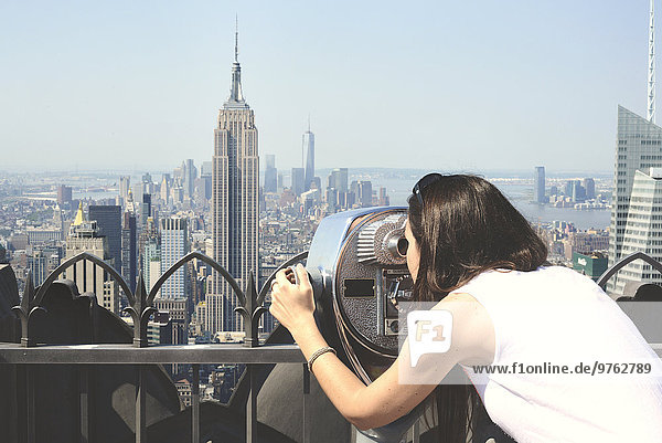 USA  New York  Frau schaut durchs Fernglas auf Manhattan mit Empire State Building