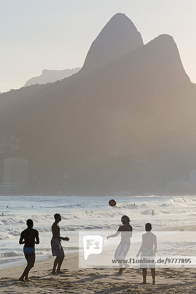 Locals playing football on Ipanema beach with the Morro dos Dois Irmaos (Two Brothers) mountains behind  Rio de Janeiro  Brazil  South America
