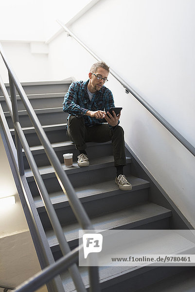 Man sitting on steps using tablet pc