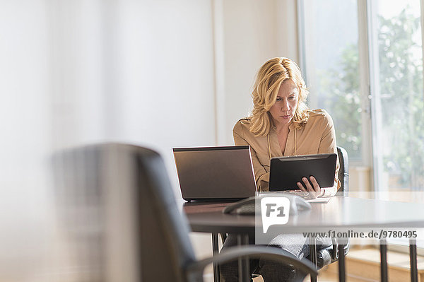 Business woman using laptop and tablet pc in office