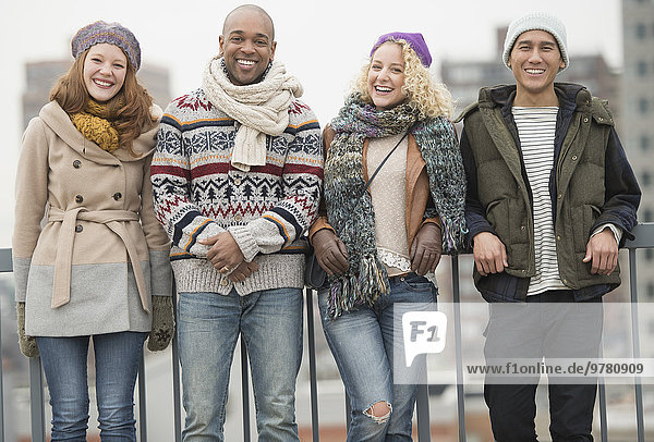 Portrait of happy friends leaning against bridge railing