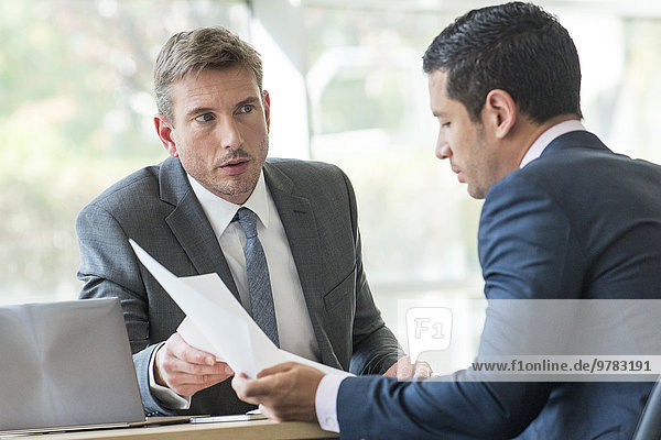 Businessmen discussing documents in meeting