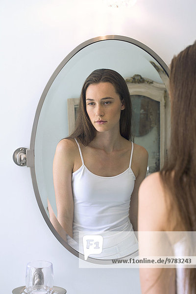 Woman's reflection in bathroom mirror