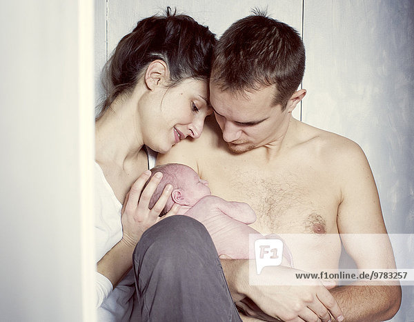 New parents sitting with newborn baby