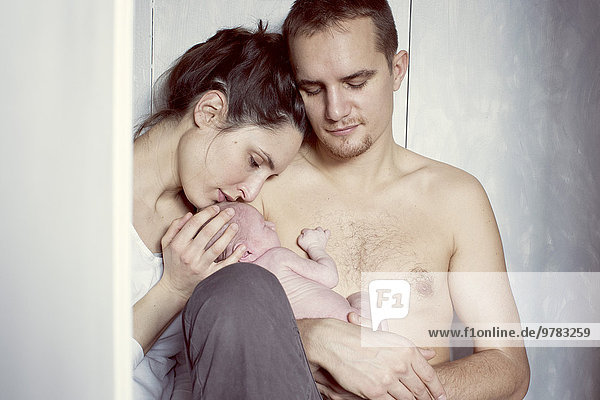 New parents sitting with newborn baby