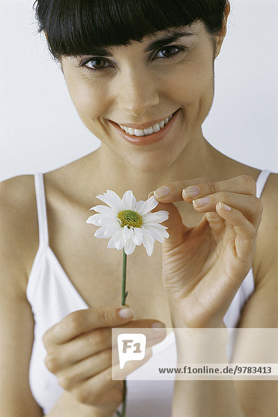 Junge Frau pflückt Blütenblätter  lächelnd  Portrait