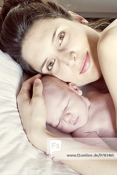 Mutter auf dem Bett liegend mit Neugeborenem  Portrait
