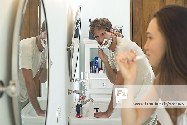 Woman brushing teeth  husband shaving