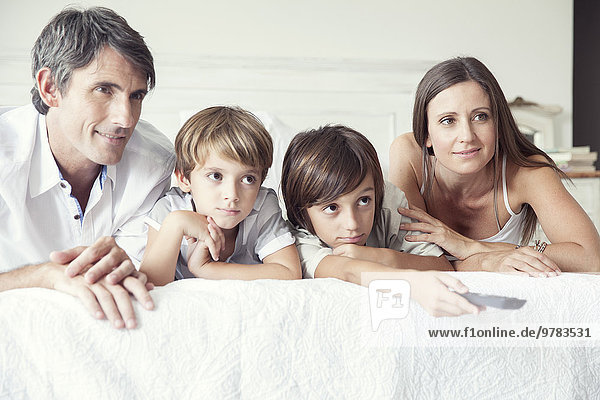 Familie beim Fernsehen im Bett  Porträt