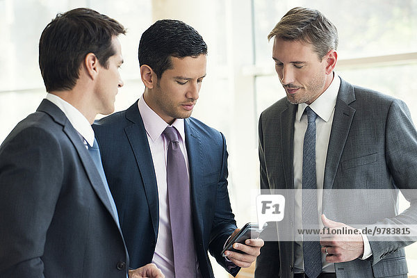 Businessman talking with colleagues  looking at smartphone