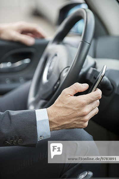 Businessman text messaging while driving  cropped