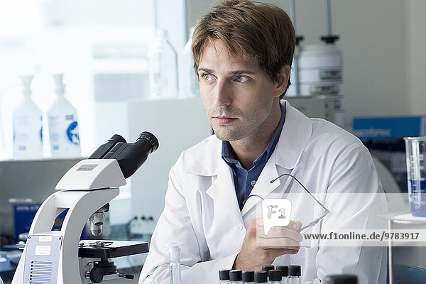 Scientist working in laboratory  looking away in thought