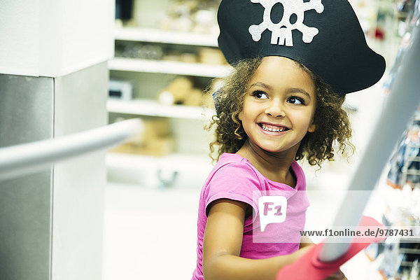 Mixed race girl playing dress-up with pirate hat and sword