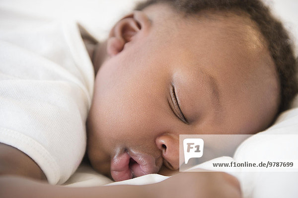 Close up of Black baby boy sleeping on bed